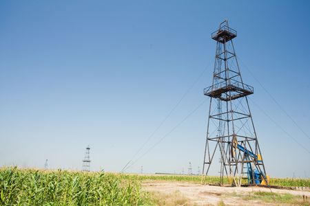 Oil well field in a middle of a corn field. Agriculture and industry.