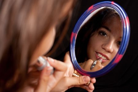 Reflection of a beautiful woman doing make-upの写真素材