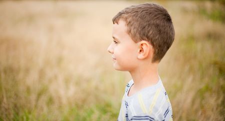 Portrait of a cute kid in profile, over a blurred nature backgroundの写真素材