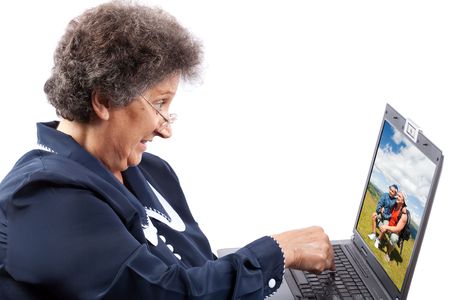 Old woman with glasses using computerの写真素材