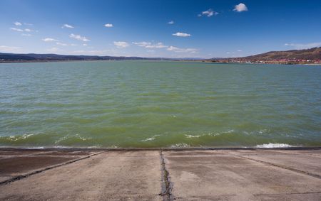 Landscape with a dam or barrage near a village and hills in the background, under beautiful blue skyの写真素材