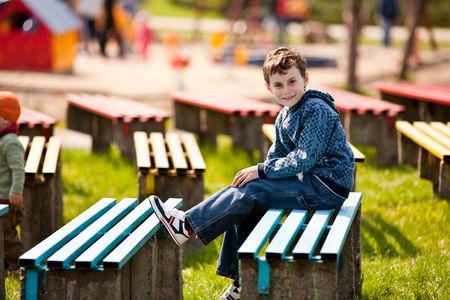 Cute schoolboy relaxing sitting on bench in a parkの写真素材