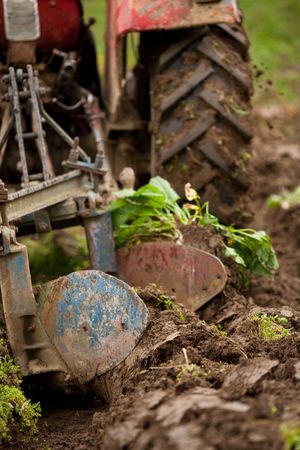 Close up of the rear end of a tractor while plowing, some motion blur present