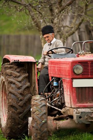 Senior farmer using an old tractor to plow his landの写真素材