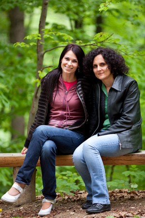 Portrait of two beautiful ladies sitting on a bench in parkの写真素材