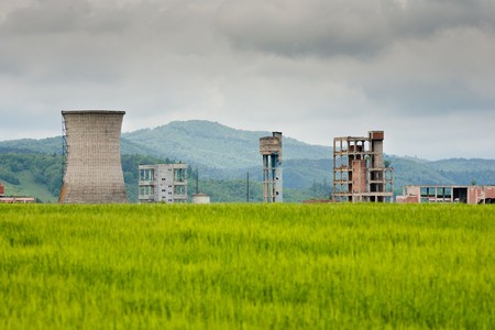 Abandoned industrial facility behind a green wheat fieldの写真素材