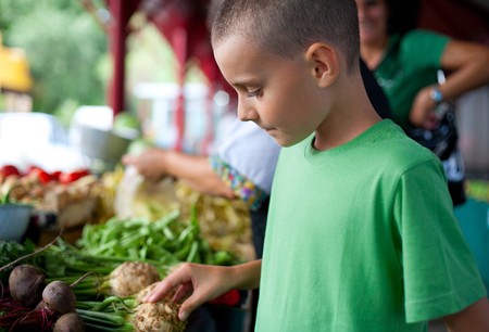 Cute boy with his mother buying fresh vegetables at the farmer's marketの写真素材
