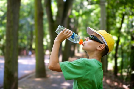 Portrait of a cute child drinking water from a bottle in the forestの写真素材