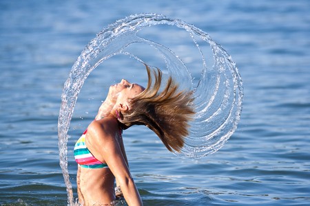Motion freeze on a girl splashing the sea water with her hairの写真素材