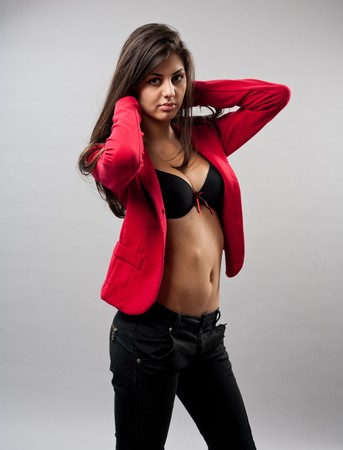 Beautiful young woman with red coat, studio shot on grayの写真素材