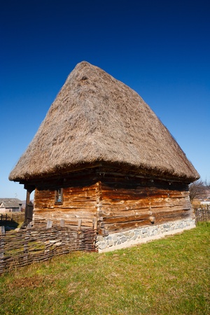 Old traditional Romanian barn or shack under blue sky - this is part of a series of images with countryside buildings in Romaniaの写真素材