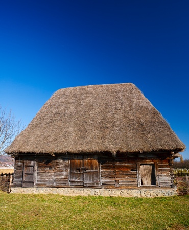 Old traditional Romanian barn or shack under blue sky - this is part of a series of images with countryside buildings in Romaniaの写真素材