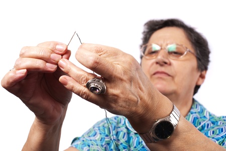 Senior woman passing the string through needle for sewingの写真素材