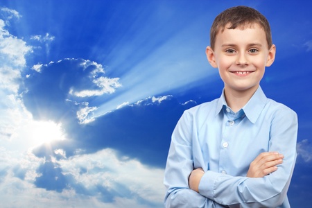 Boy with blue shirt on blue sky with clouds backgroundの写真素材