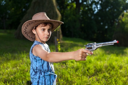 Cute little boy with hat playing the cowboy, outdoorの写真素材