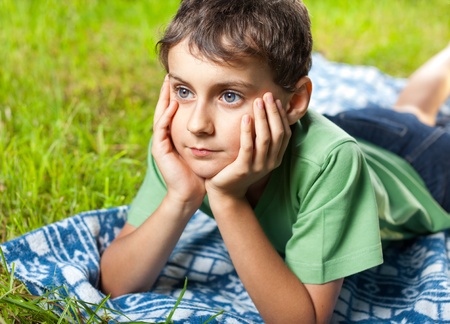 Closeup portrait of an expressive boy sitting on a blanket in grassの写真素材