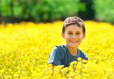 Portrait of a beautiful boy outdoor in a field of yellow flowersの写真素材