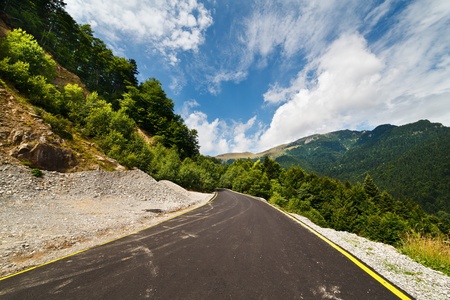 Landscape with a road through mountains under blue sky with cloudsの写真素材