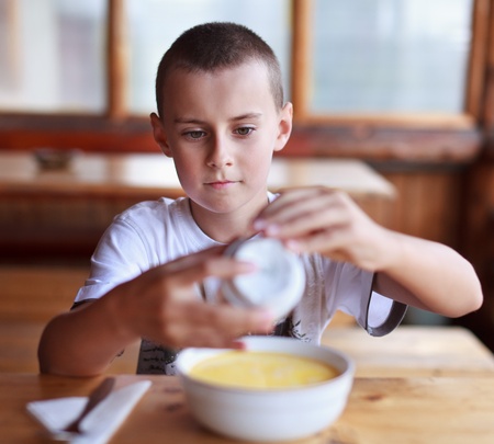 Boy eating soup for dinner in a rustic restaurant outdoorの写真素材
