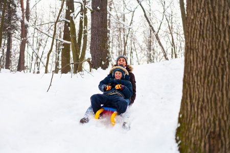 Mother and son riding a sledge in a holiday winter dayの写真素材