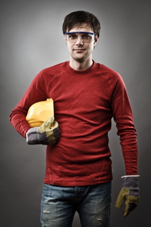 Young blue collar worker with yellow protective helmet and glovesの写真素材