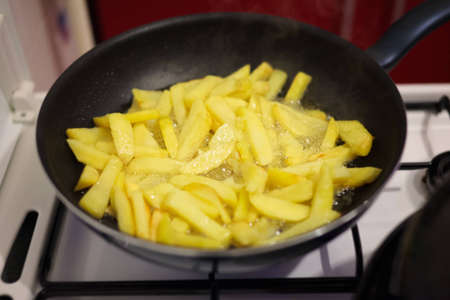 Preparing french fries in the frying pan, with selective focus