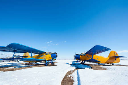 Old airplanes parked on a meadow with snow in a sunny day