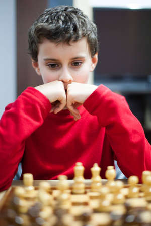 Closeup portrait of a school boy playing chess, selective focus