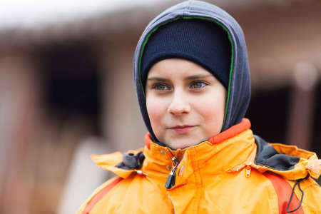 Closeup portrait of a cute boy with coat and hood outdoorの写真素材