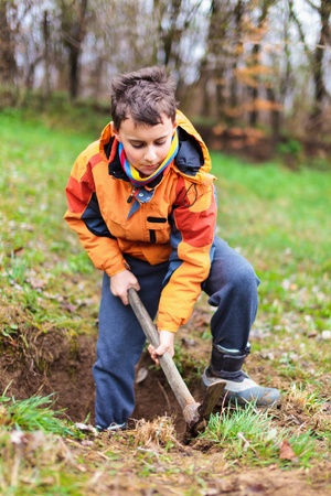 Boy digging on a grass field in the countrysideの写真素材
