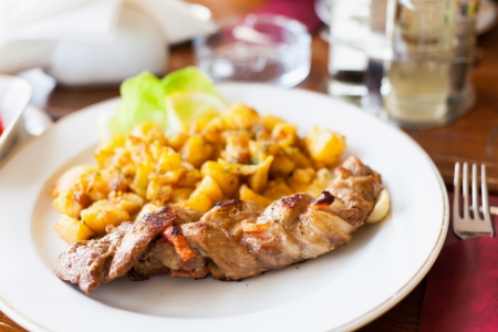 Braided pork tenderloin with baked potatoes garnishの写真素材