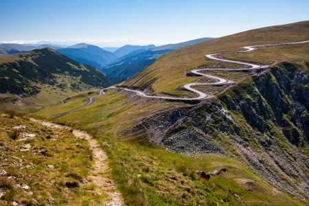 Landscape with a winding road and a trail on mountainsの写真素材