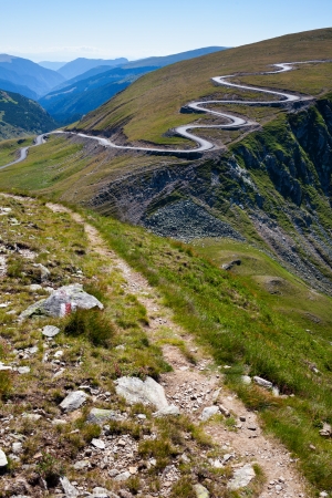 Landscape with a winding road and a trail on mountainsの写真素材