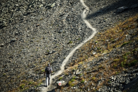 Man walking on mountain trail, hiking to the topの写真素材