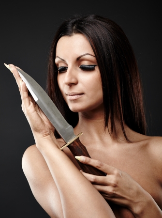 Arab woman holding a knife in her hand in glamour pose. Gray  backgroundの写真素材