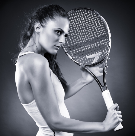 A monochrome studio shot of a young female tennis player holding the racketの写真素材