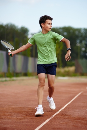 Child hitting the ball with the forehand on a dross courtの写真素材