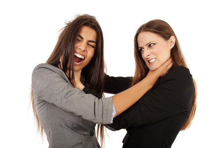 Portrait of two attractive businesswomen fighting isolated on whiteの写真素材