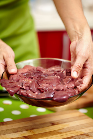 Woman cook holding a bowl with raw chicken liver for cookingの写真素材