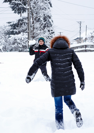 Teenage boy playing in the snow with his motherの写真素材