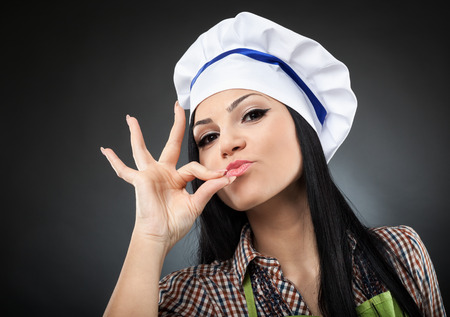 Beautiful latino woman chef making "it's delicious" sign, closeupの写真素材