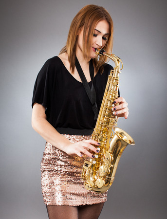 Beautiful blond woman saxophone player studio closeup shotの写真素材