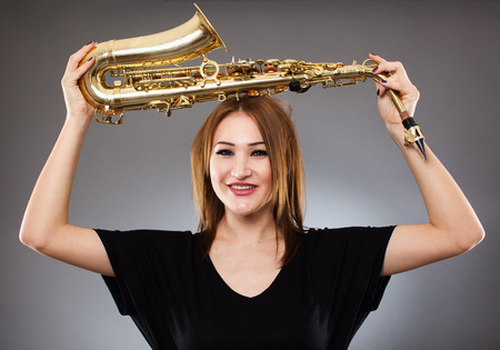 Beautiful blond woman saxophone player studio closeup shotの写真素材