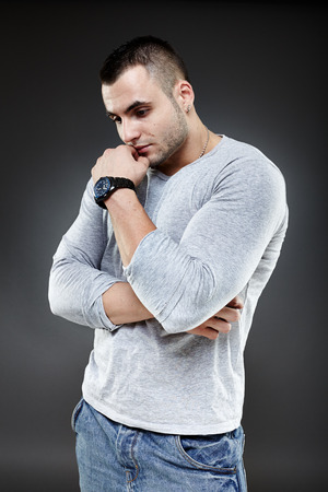Portrait of a pensive young man over gray backgroundの写真素材