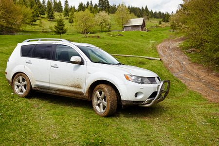 White SUV in a picturesque landscape with a muddy roadの写真素材