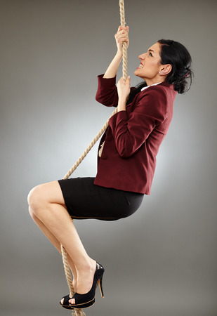Latin businesswoman climbing on a rope, conceptual image of career achievementの写真素材