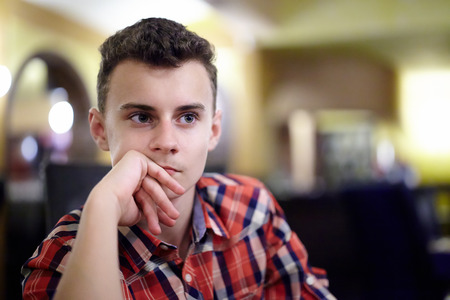 Closeup portrait of a pensive teenage boy in a restaurantの写真素材