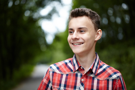 Closeup of a handsome teenage boy outdoor in a parkの写真素材