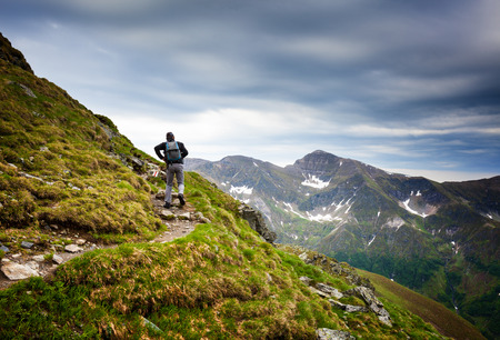 Young man hiking into the mountains in a spectacular landscapeの写真素材