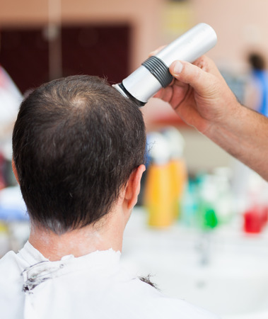 Caucasian man in a barber shop getting a very short haircutの写真素材
